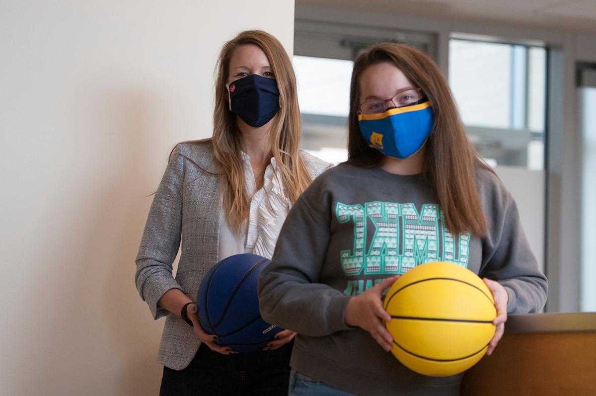 Student and professor hold basketballs